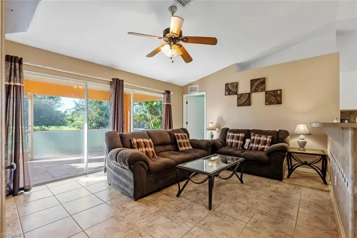 Tiled living room featuring vaulted ceiling and ceiling fan