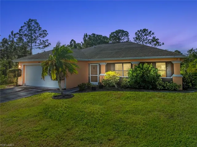 Ranch-style house featuring a lawn and a garage
