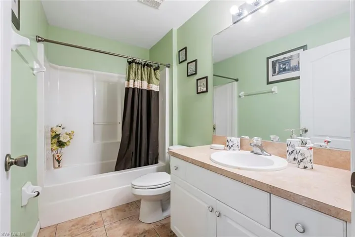 Full bathroom with toilet, shower / bath combo, vanity, and tile patterned floors