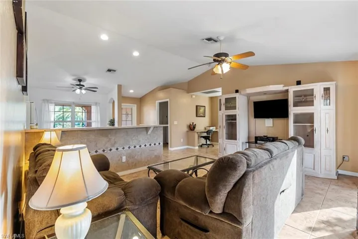 Tiled living room with lofted ceiling and ceiling fan