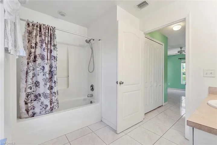 Bathroom featuring vanity, tile patterned floors, and shower / bathtub combination with curtain