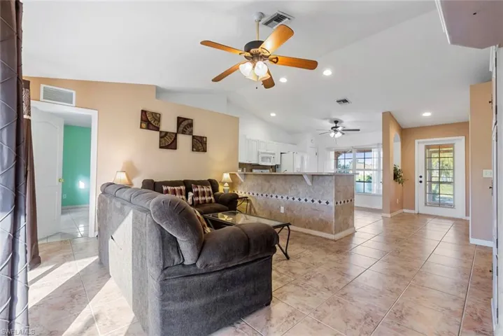 Tiled living room featuring lofted ceiling and ceiling fan