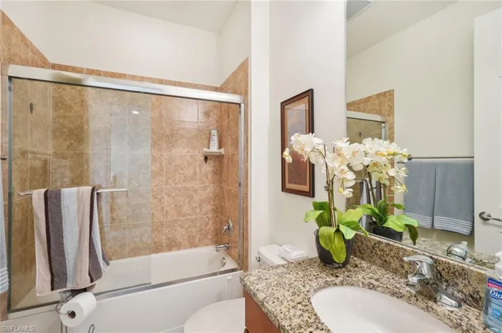 Bathroom featuring toilet, visible vents, bath / shower combo with glass door, and vanity