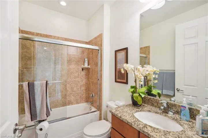 Full bathroom with toilet, shower / bath combination with glass door, and vanity