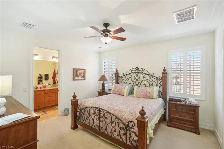 Bedroom with light carpet, multiple windows, and visible vents