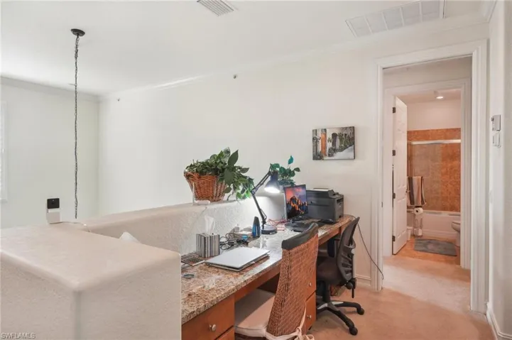 Home office featuring visible vents, ornamental molding, and light colored carpet
