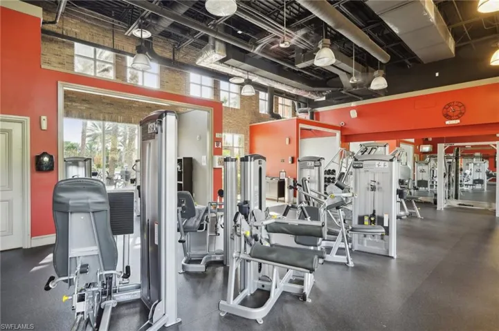 Exercise room featuring a towering ceiling, brick wall, and baseboards
