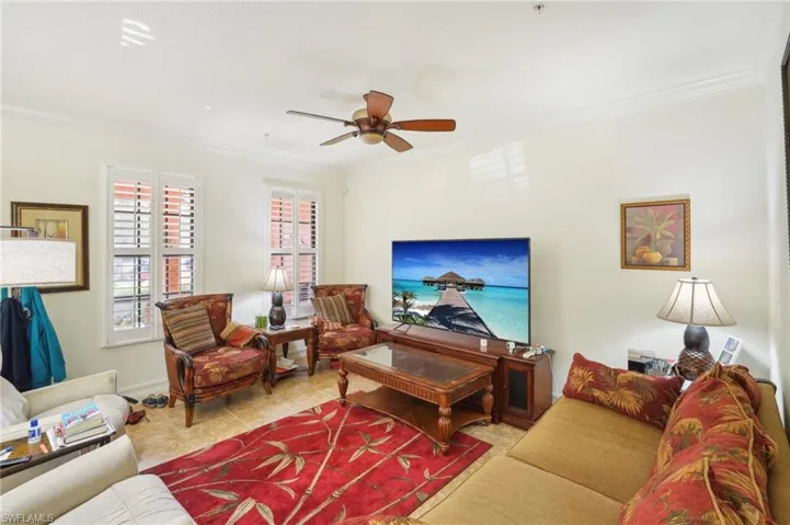 Living area with ceiling fan, tile patterned flooring, and crown molding