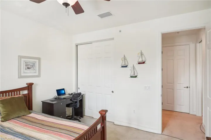 Bedroom featuring a ceiling fan, visible vents, a closet, and light colored carpet