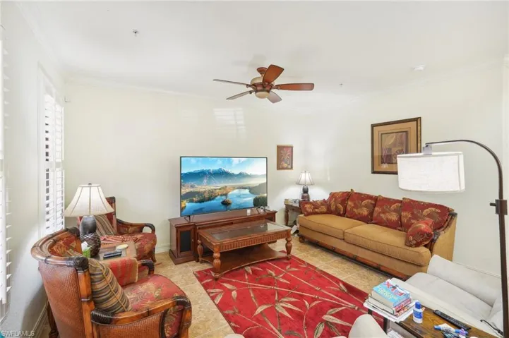 Living room featuring a ceiling fan and crown molding