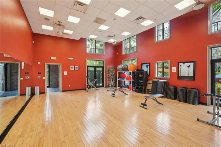 Exercise room featuring wood-type flooring, visible vents, a drop ceiling, and a high ceiling