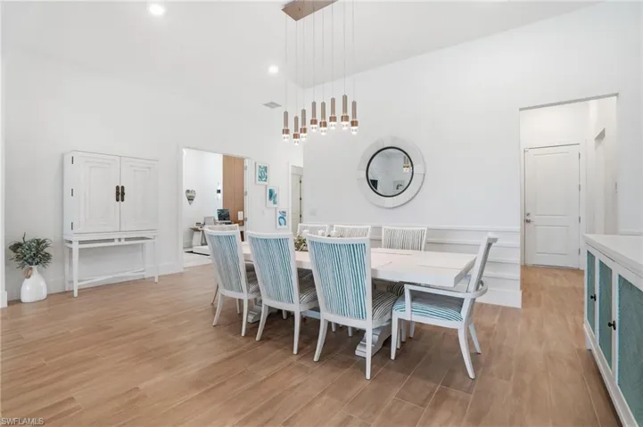 Dining area featuring wood-finish flooring, white walls, and a modern linear chandelier