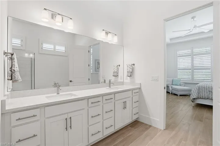 Dual vanity with white cabinetry, stone-finish countertops, and chrome fixtures