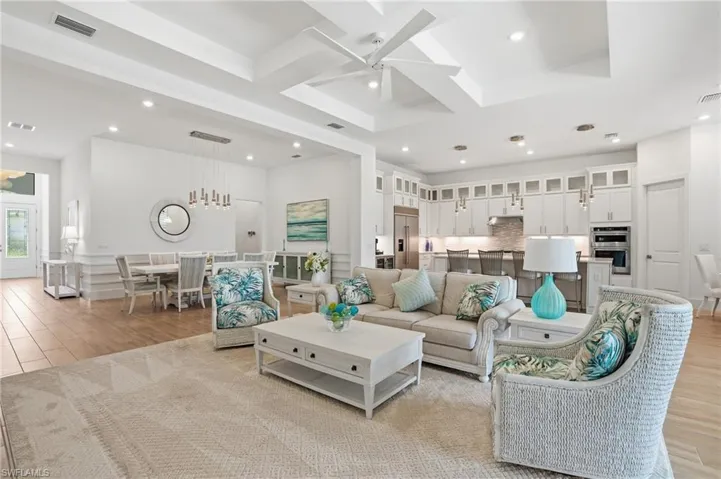 Spacious open-concept living area featuring a tray ceiling with a contemporary fan, recessed lighting, and wood-finish flooring