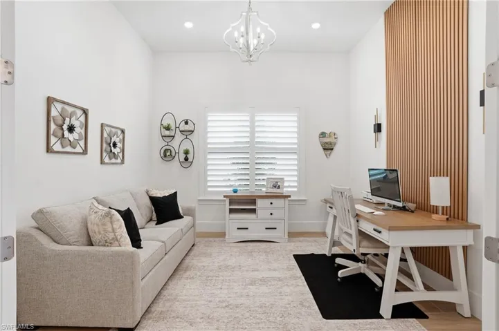 Spacious interior room featuring a decorative wood slat accent wall, recessed lighting, and a contemporary chandelier