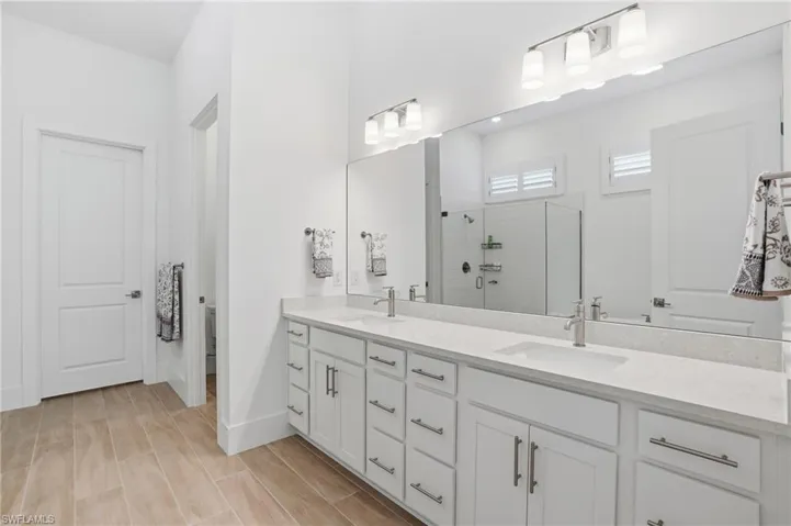 Spacious bathroom featuring a dual vanity with light-toned countertops, contemporary brushed nickel faucets, and extensive storage cabinetry