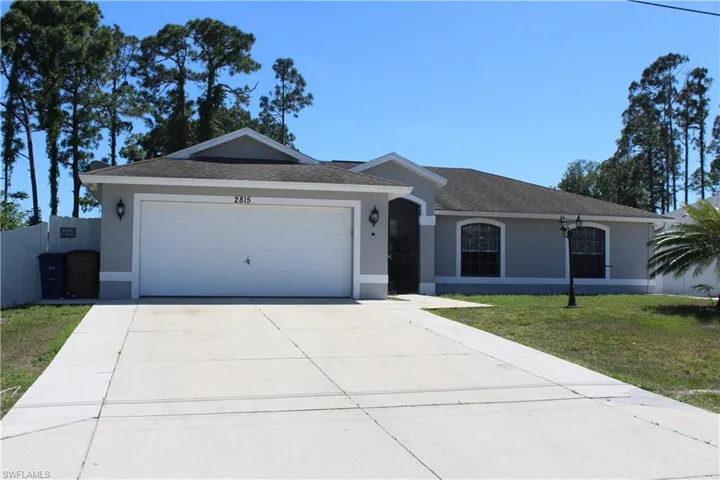Ranch-style house featuring a front yard and a garage