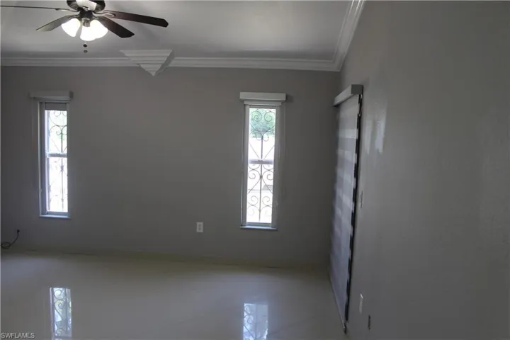 Tiled spare room featuring ornamental molding and ceiling fan