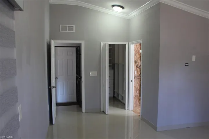 Hallway with a towering ceiling, tile flooring, and ornamental molding