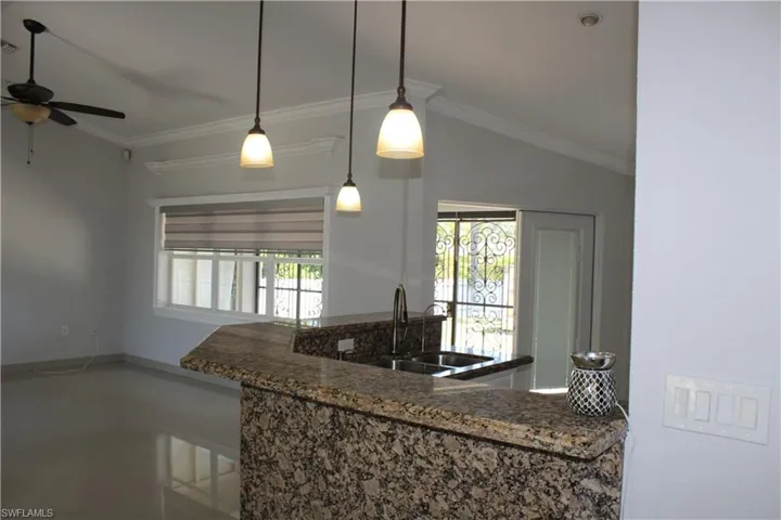 Kitchen featuring dark stone counters, ceiling fan, tile flooring, sink, and ornamental molding