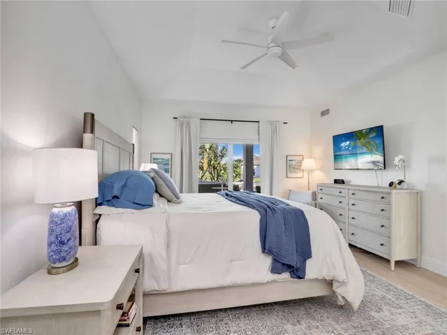 Bedroom featuring light hardwood / wood-style flooring, a raised ceiling, and ceiling fan