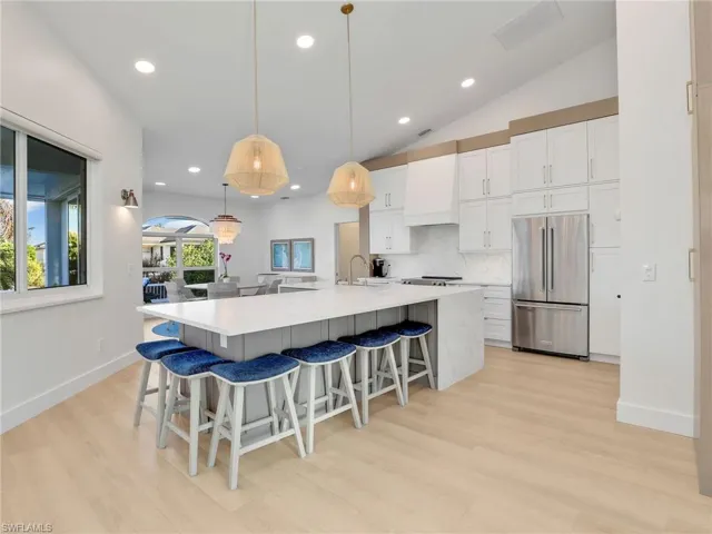 Kitchen featuring white cabinetry, high quality fridge, decorative light fixtures, and custom exhaust hood