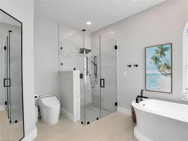 Bathroom featuring toilet, tile patterned floors, and shower with separate bathtub