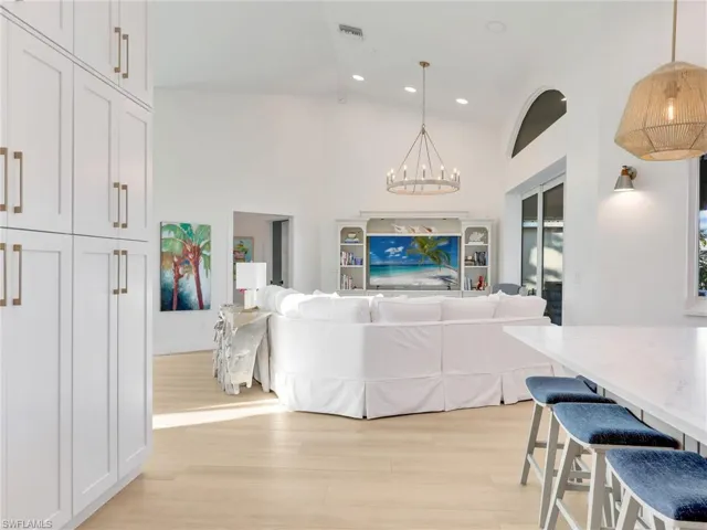 Living room with a notable chandelier, light hardwood / wood-style floors, and high vaulted ceiling