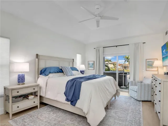 Bedroom with a raised ceiling, access to outside, ceiling fan, and light hardwood / wood-style flooring