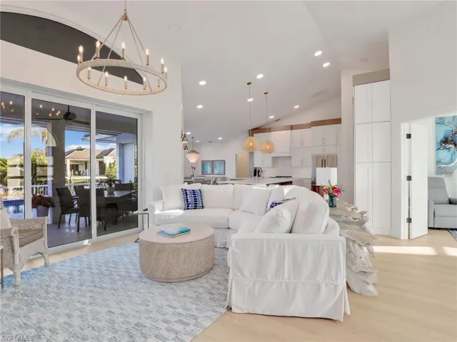 Living room with sink, a chandelier, high vaulted ceiling, and light hardwood / wood-style flooring