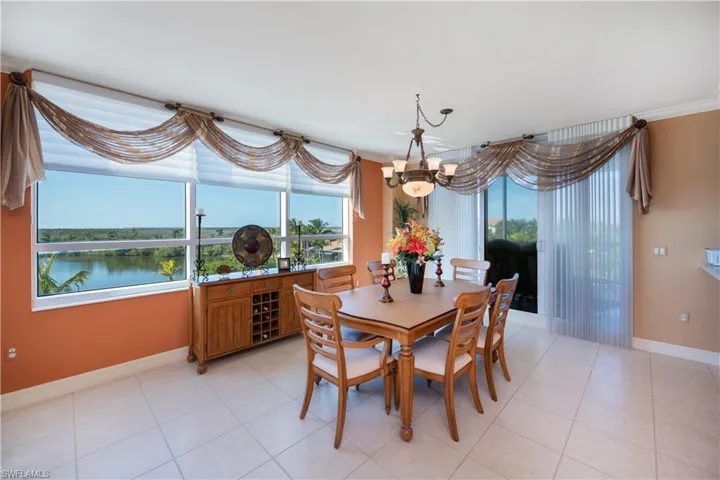 Dining space with ornamental molding, light tile patterned flooring, a water view, and a chandelier