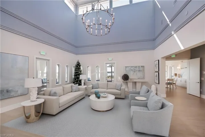 Living area featuring wood finished floors, a towering ceiling, and a chandelier