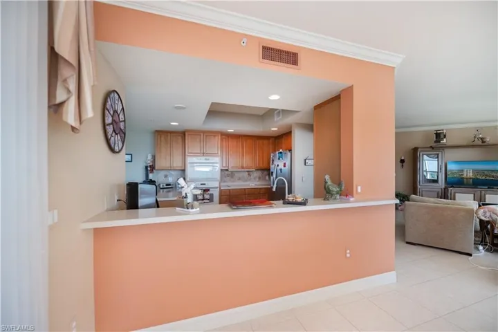 Kitchen featuring tasteful backsplash, stainless steel fridge with ice dispenser, a raised ceiling, open floor plan, and recessed lighting
