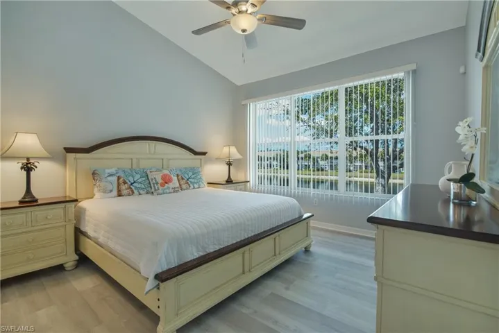 Bedroom with a ceiling fan, lofted ceiling, and light wood finished floors