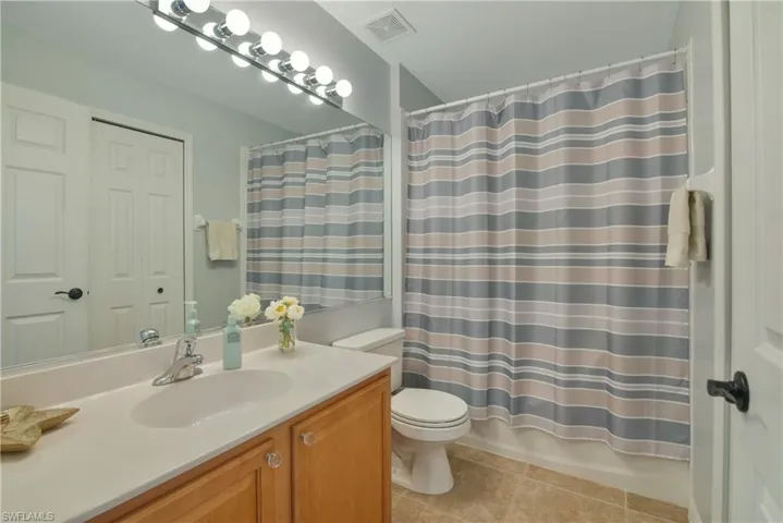 Full bath featuring vanity, light tile patterned flooring, and shower / tub combo with curtain