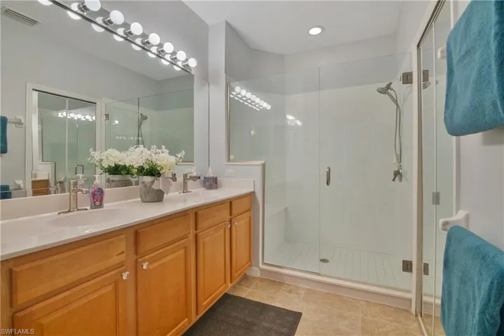Bathroom with double vanity, a stall shower, and light tile patterned flooring