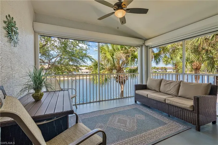 Sunroom with a water view, a textured wall, and lofted ceiling