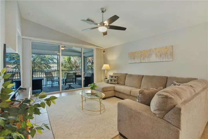 Living area with a ceiling fan, vaulted ceiling, a sunroom, and tile patterned flooring