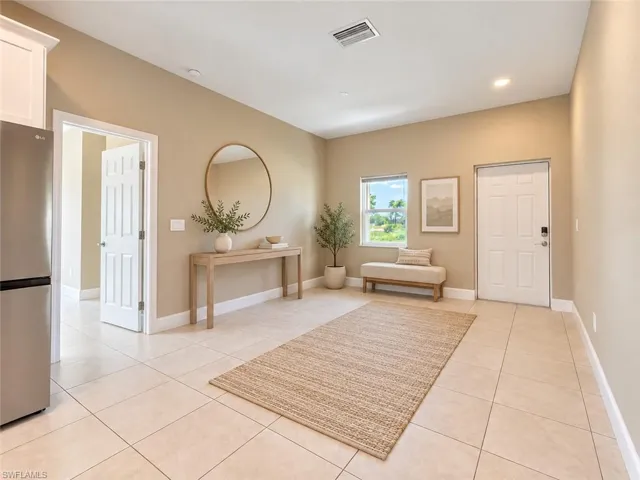 Light-colored tile flooring, recessed ceiling lighting, a tall white paneled door, and a full-light window