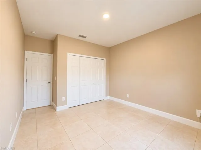 Neutral wall paint, recessed ceiling lighting, tile flooring, white interior door, and bi-fold closet doors