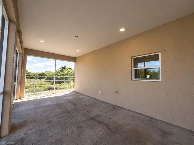 Screened outdoor area with concrete flooring, recessed lighting, and a stucco-textured wall