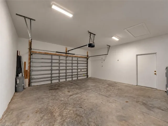 Spacious garage with concrete flooring, overhead lighting, and an automatic garage door opener