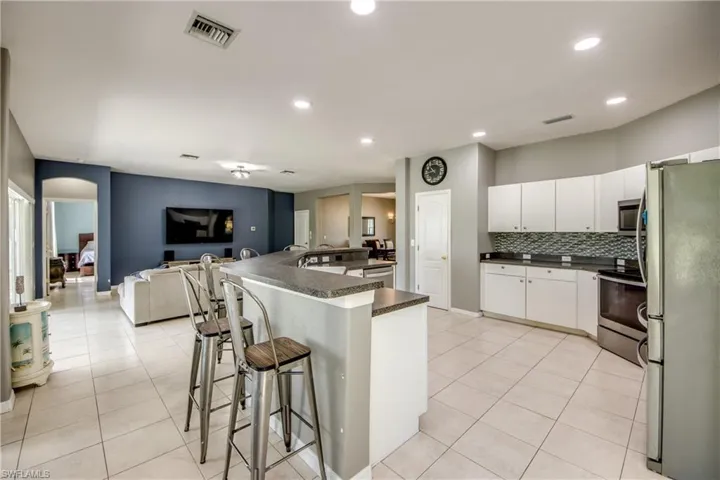 Kitchen with dark countertops, stainless steel appliances, white cabinets, a kitchen bar, and open floor plan