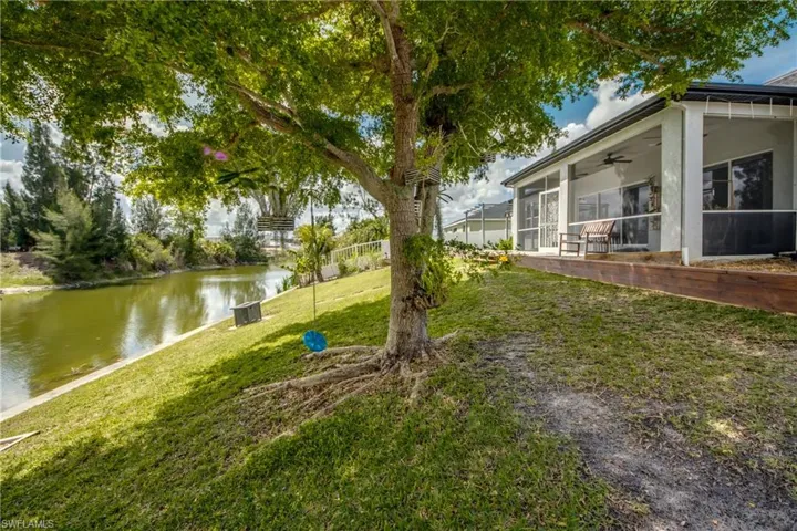 View of grassy yard featuring a sunroom, a water view, and ceiling fan