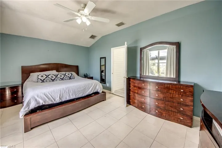 Bedroom with lofted ceiling, a ceiling fan, and light tile patterned flooring