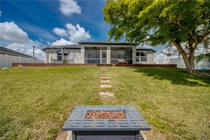 Rear view of property with ceiling fan, a sunroom, a fenced backyard, and an outdoor fire pit