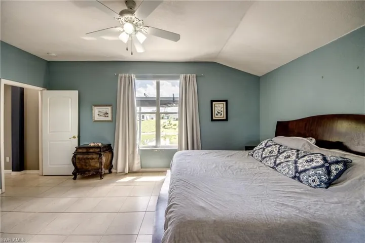 Bedroom featuring lofted ceiling, ceiling fan, and light tile patterned floors