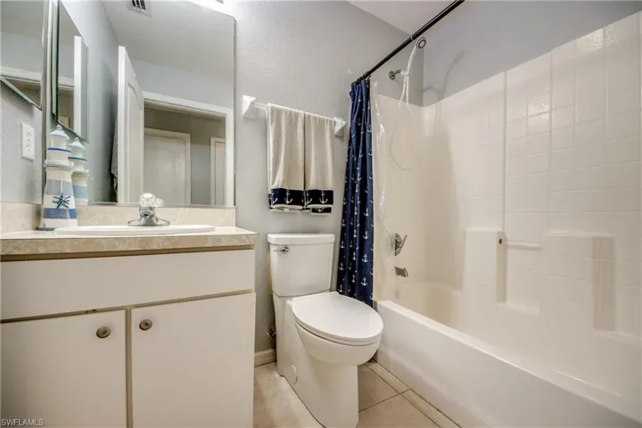Bathroom with vanity, shower / tub combo, light tile patterned floors, and a textured wall