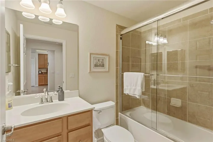 Full bathroom featuring vanity, a textured wall, and enclosed tub / shower combo