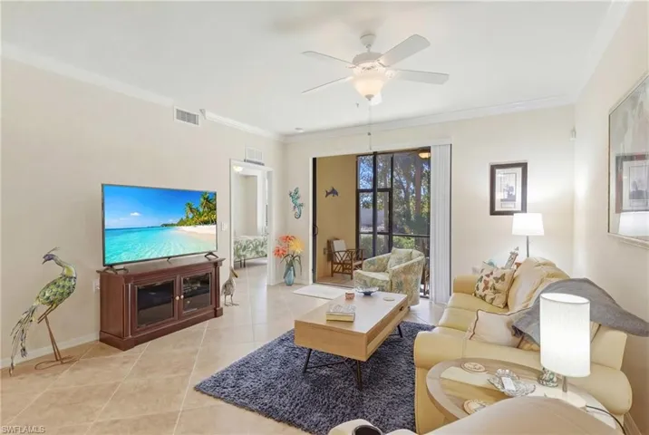 Tiled living room featuring ornamental molding and a ceiling fan